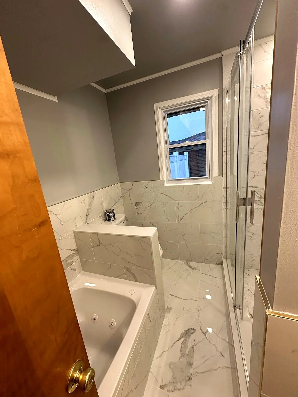 Finished bathroom with frameless glass shower and marble tile